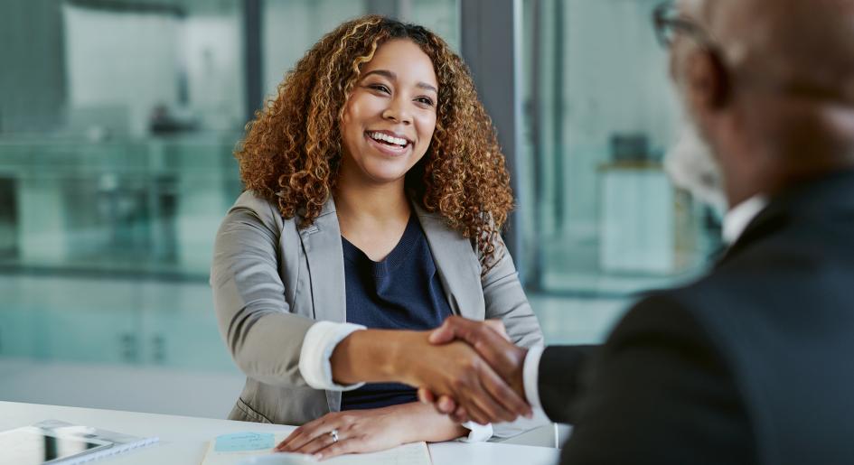 Two people shake hands at a job interview