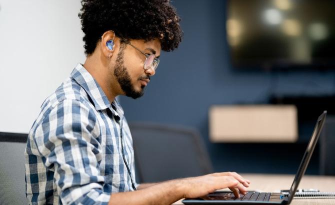 Someone with heaing aid, using a laptop