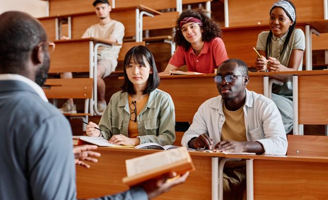 Students sit in a lecture hall listening to a professor