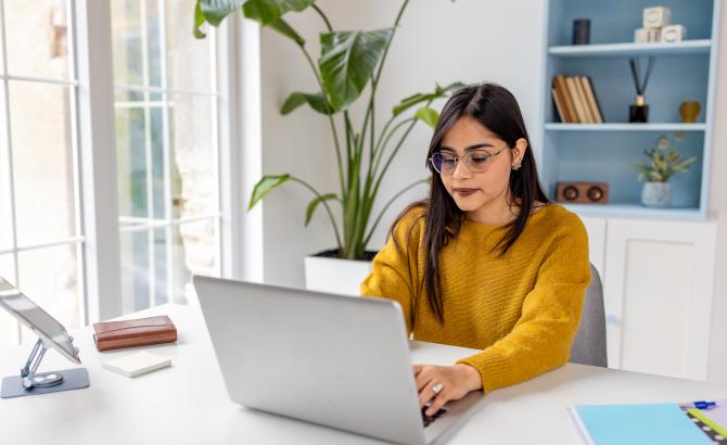 A woman types on a laptop